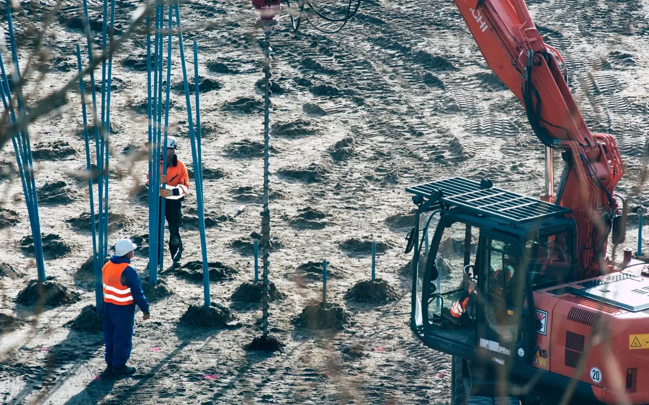 Excavadora y equipo de perforación trabajando en terreno para una investigación geotécnica